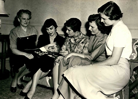 Ruth Morton Harris sharing a magazine with a group of women