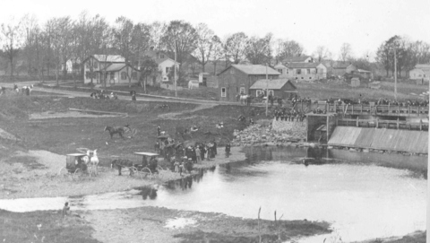 Public baptism in progress below old mill bridge - around 1900